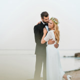 wedding couple cuddling on sandy beach near ocean