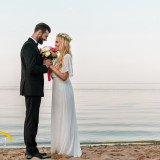 side view of affectionate wedding couple standing with bouquet o
