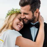 affectionate wedding couple in suit and white dress hugging on b